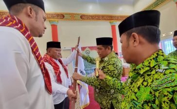 Ketua Pengurus Wilayah Dewan Masjid Indonesia (DMI) Sumatera Utara Irhamuddin Siregar menyerahkan bendera pataka DMI kepada Ketua PD DMI Kabupaten Karo Meliala Purba. (karodaily/adhif)
